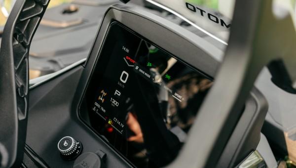 Mounted colour instrument with speed, parked gear, tachometer and fuel information is visible behind the handlebar.
